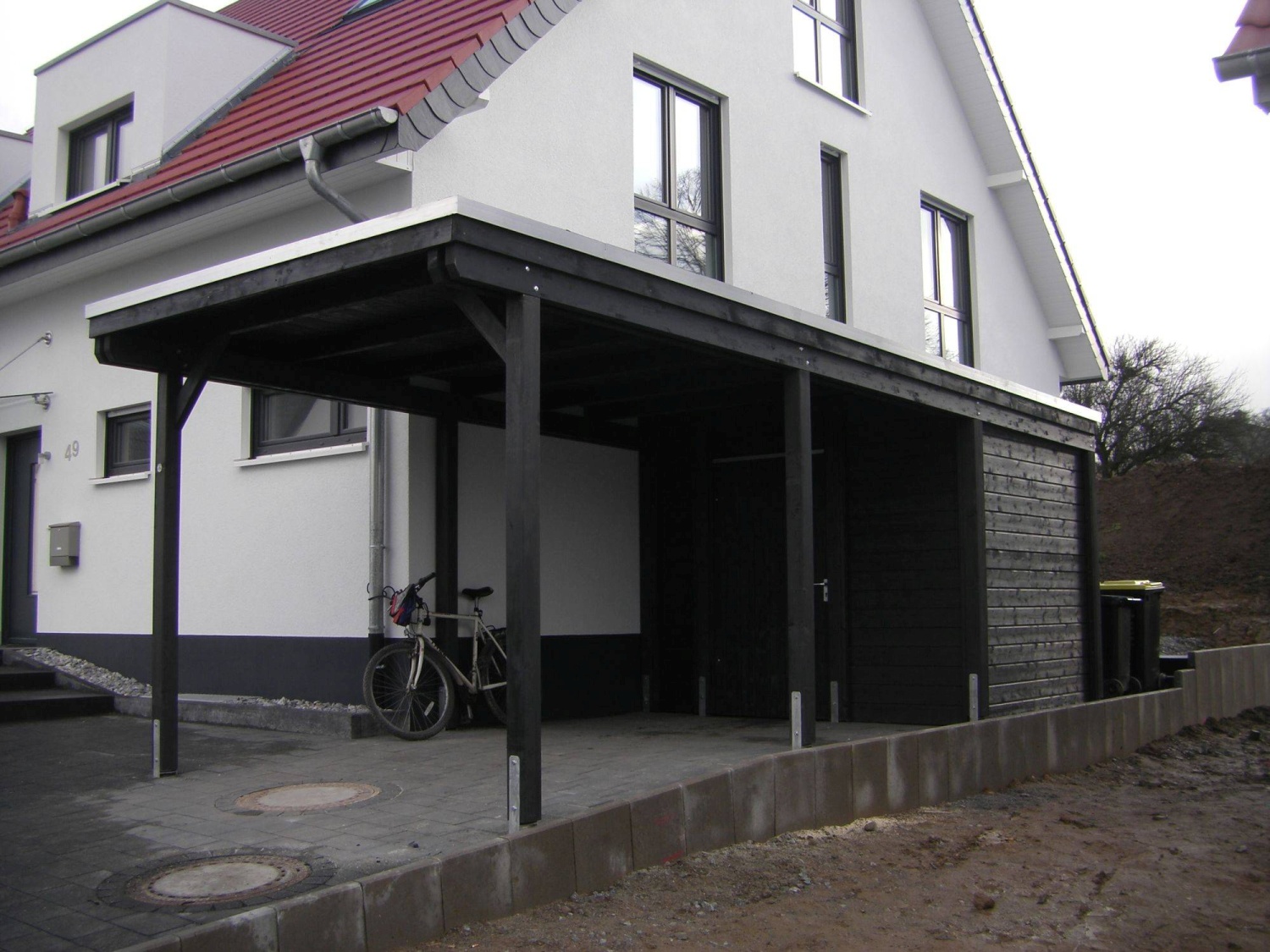Dunkel lasierter Carport mit Abstellraum